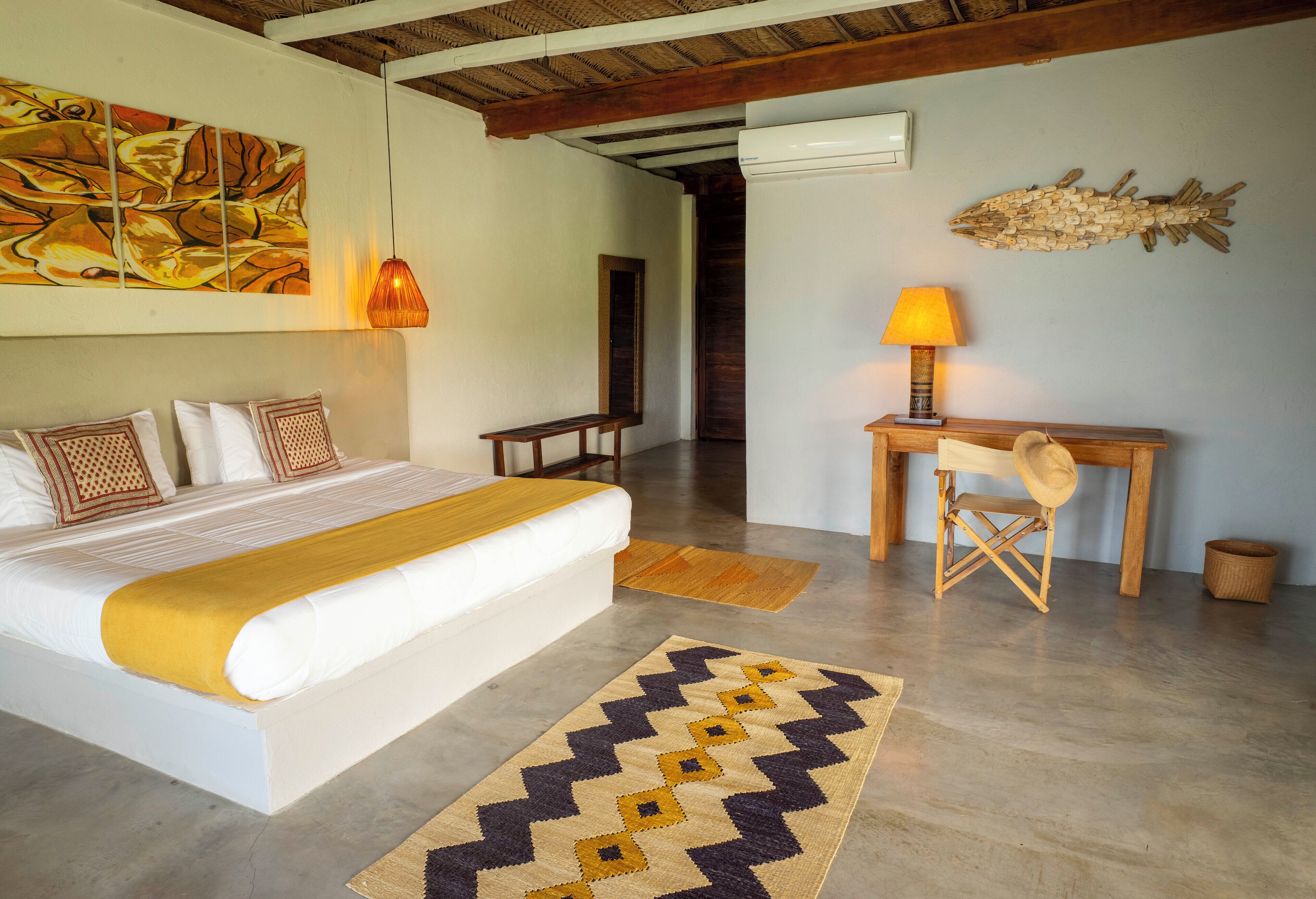 A bedroom with a bed, a desk, a lamp, and a rug.