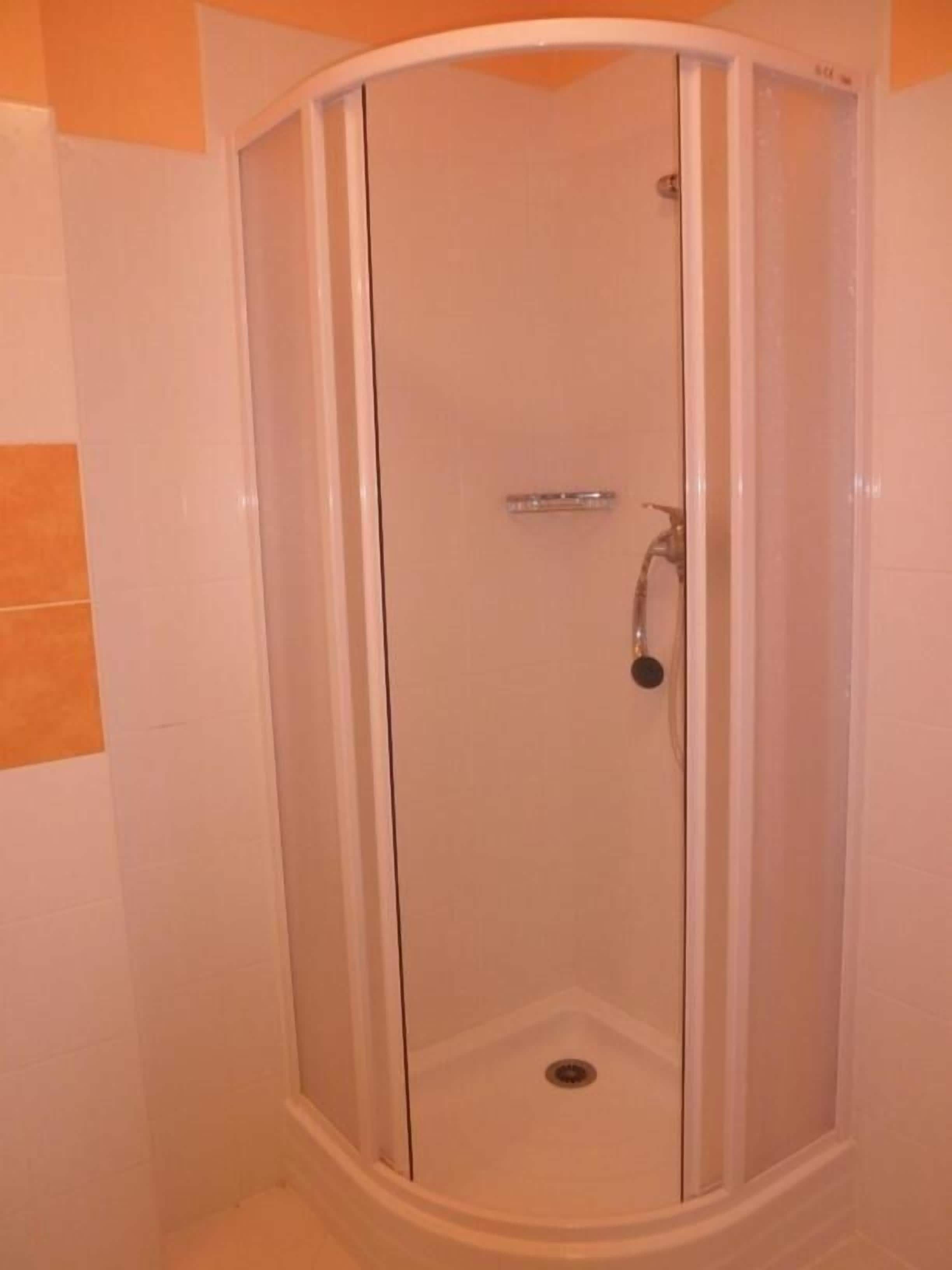 A glass-enclosed shower stall with a white door and a single showerhead.