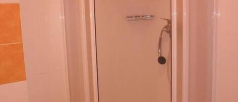 Un box de ducha con paredes de vidrio, puerta blanca y un cabezal de ducha.