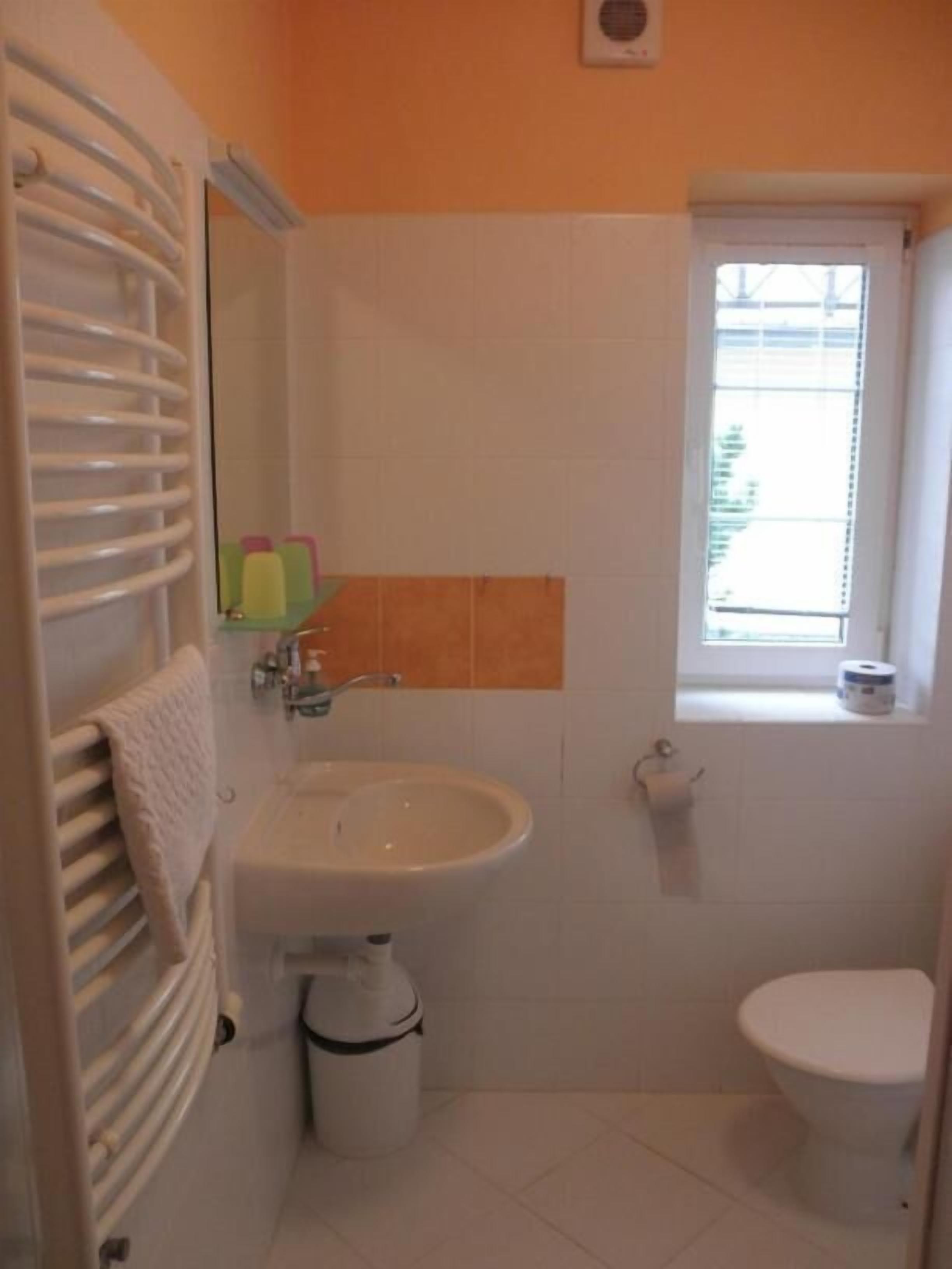 A small bathroom with a sink, toilet, and a window.