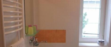 A small bathroom with a sink, toilet, and a window.