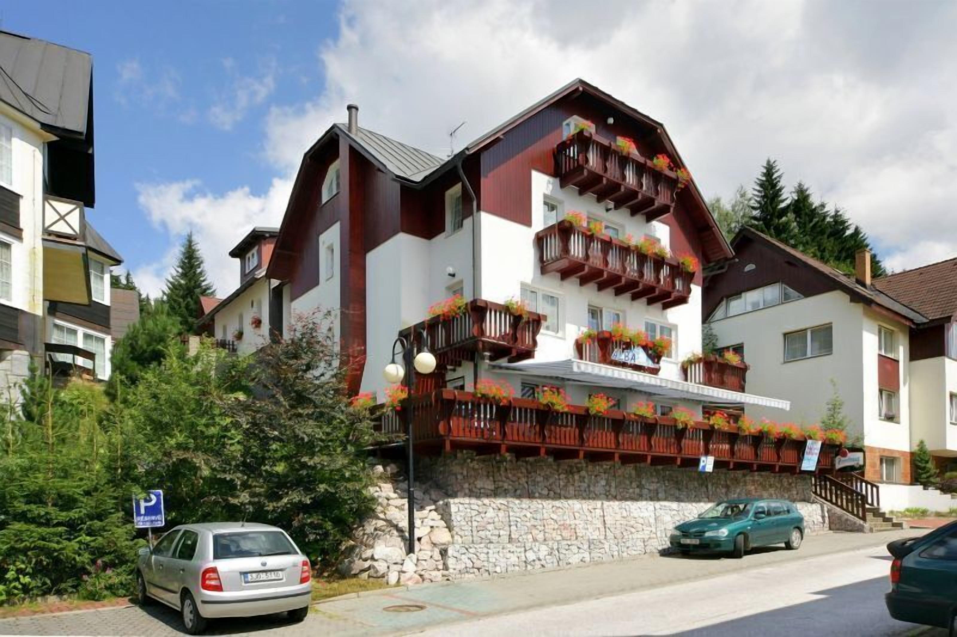 A multi-story building with balconies, a stone base, and a parking sign.