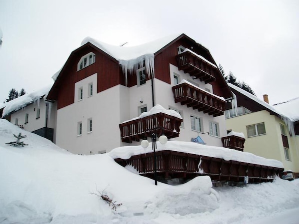 A multi-story building with balconies and a snow-covered roof. - Pension Alba (Spindleruv Mlyn)