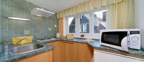 A kitchen with a sink, microwave, and cabinets.