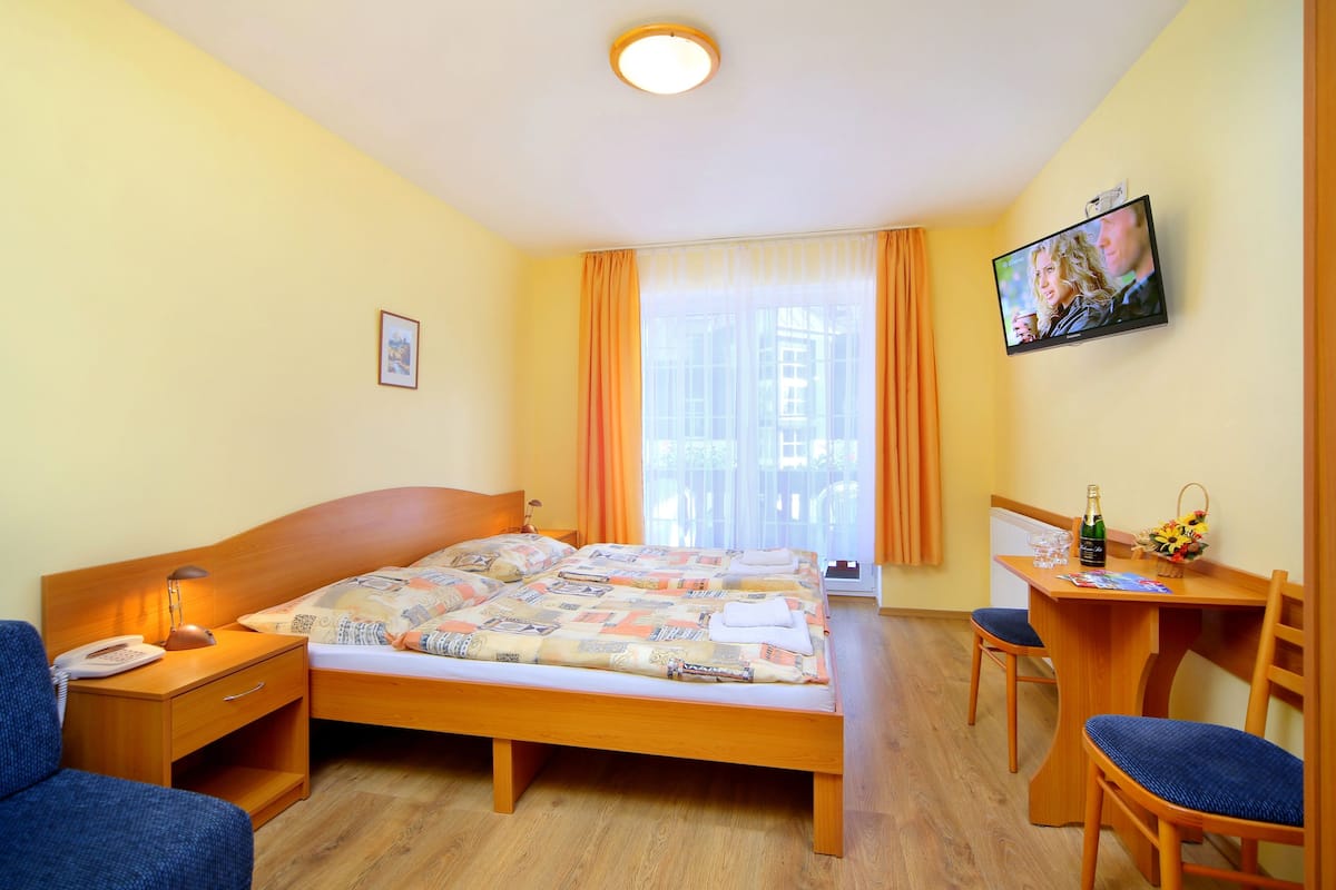 A hotel room with a bed, a desk, a chair, a television, and a window with curtains.