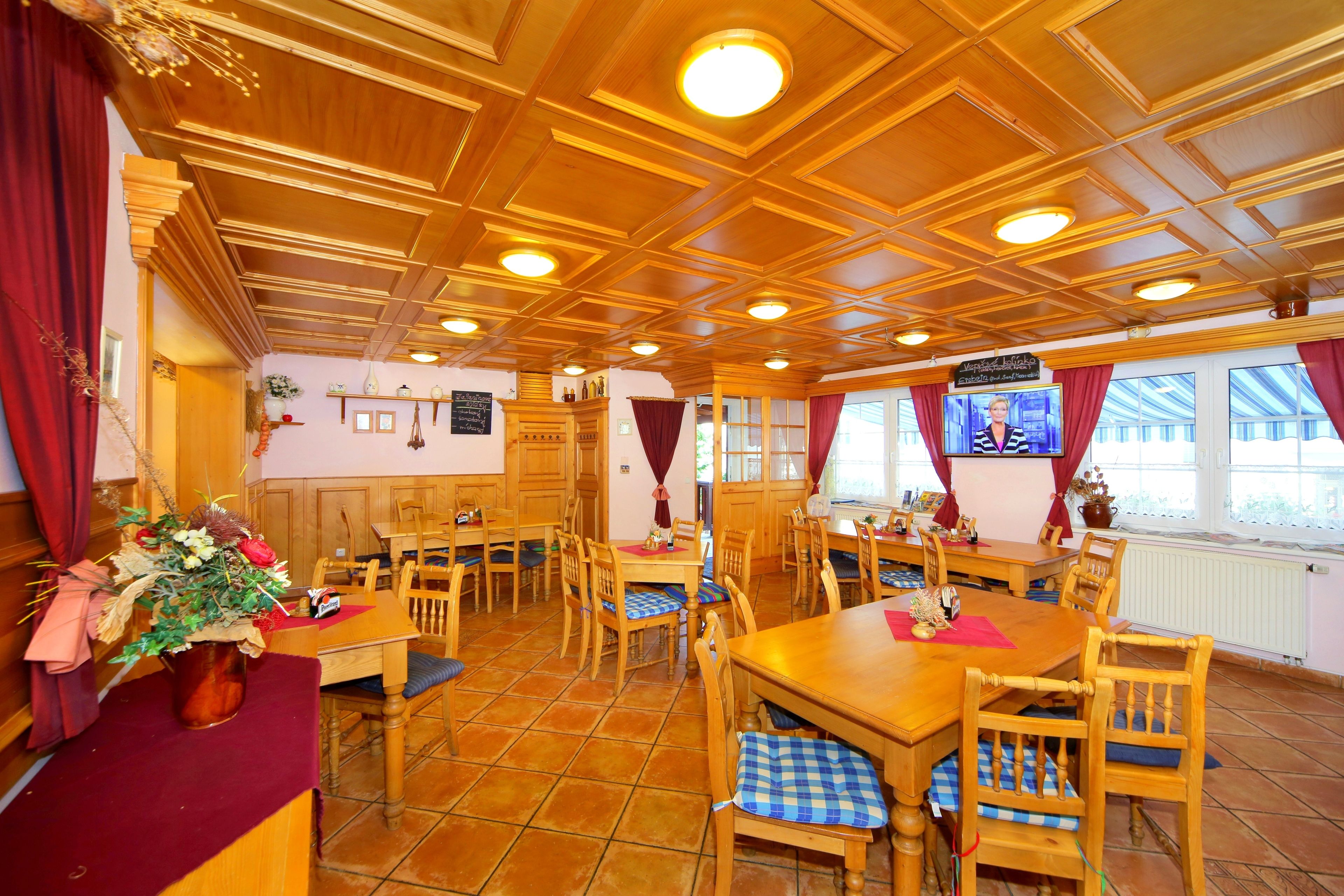 Un restaurante con mesas y sillas de madera, una cortina roja y un cartel en la pared.