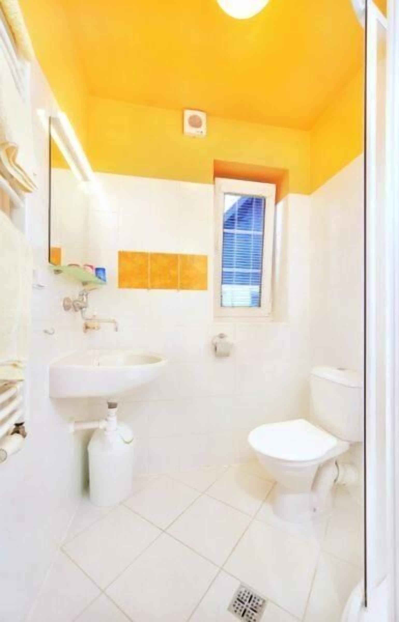Un baño con lavamanos, inodoro y ventana con persianas.
