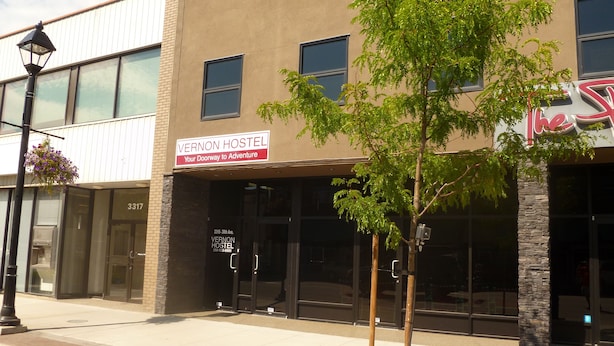 A building with a sign reading "VERNON HOSTEL Your Doorway to Adventure" and a tree in front. - Vernon Hostel (Vernon)