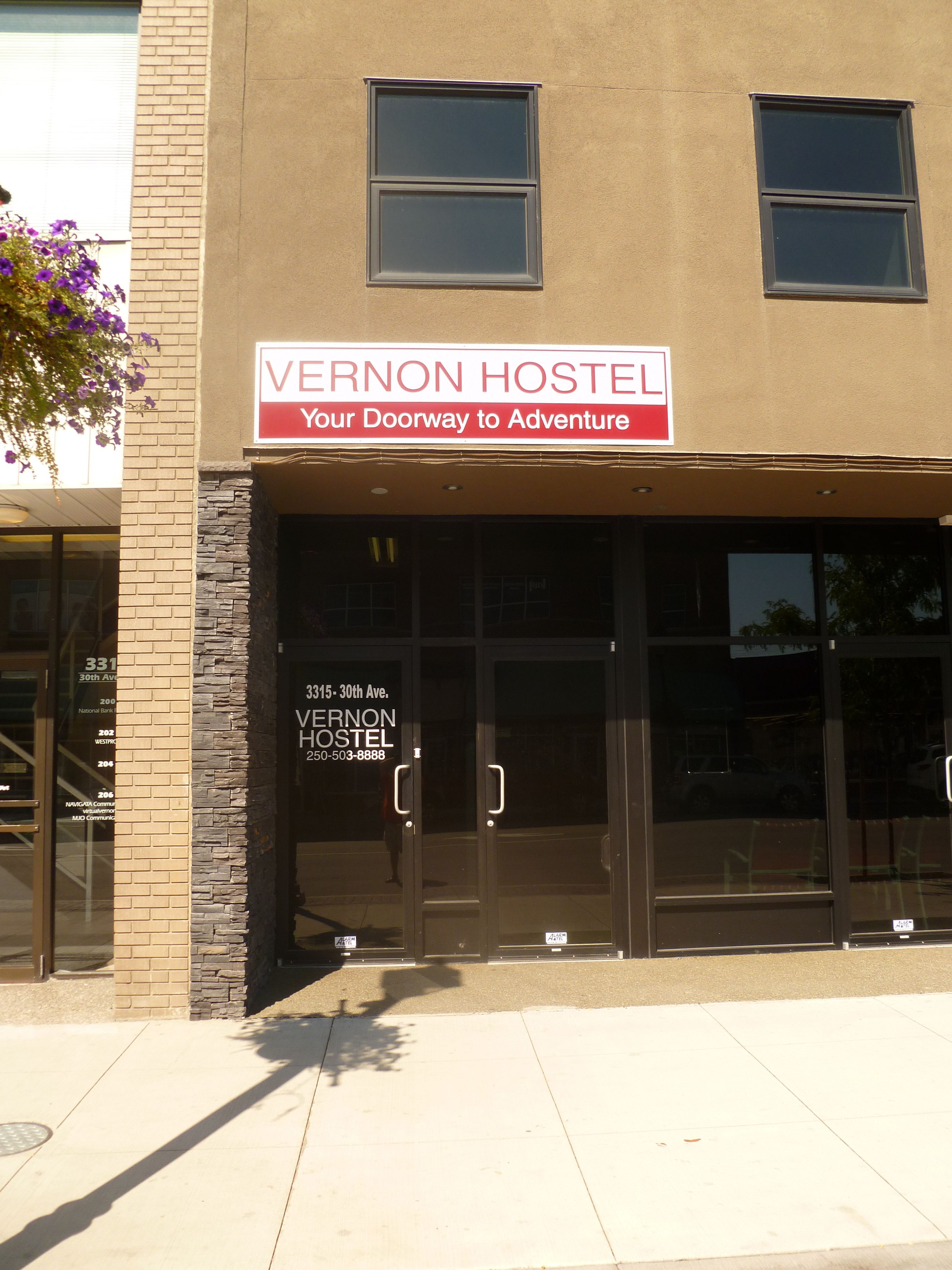 The exterior of Vernon Hostel with a sign stating "Your Doorway to Adventure."