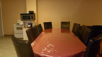 A conference room with a long table, chairs, a microwave, and a small kitchenette.