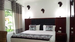 Een slaapkamer met een groot bed, twee nachtkastjes, een houten hoofdbord en decoratieve muurkunst.