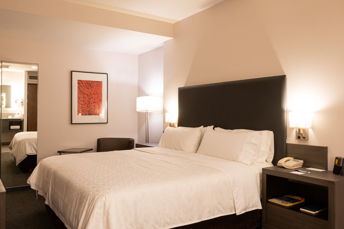 A hotel room with a large bed, bedside tables, a desk, and a chair.