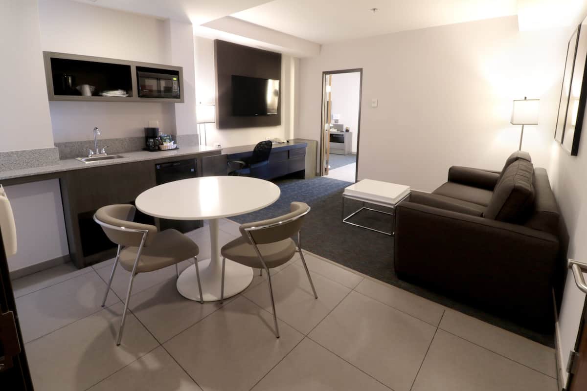 A modern kitchen with a dining area, a sofa, and a TV.