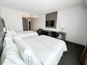 Une chambre d’hôtel avec deux lits, un bureau, une chaise, une télévision et une lampe.