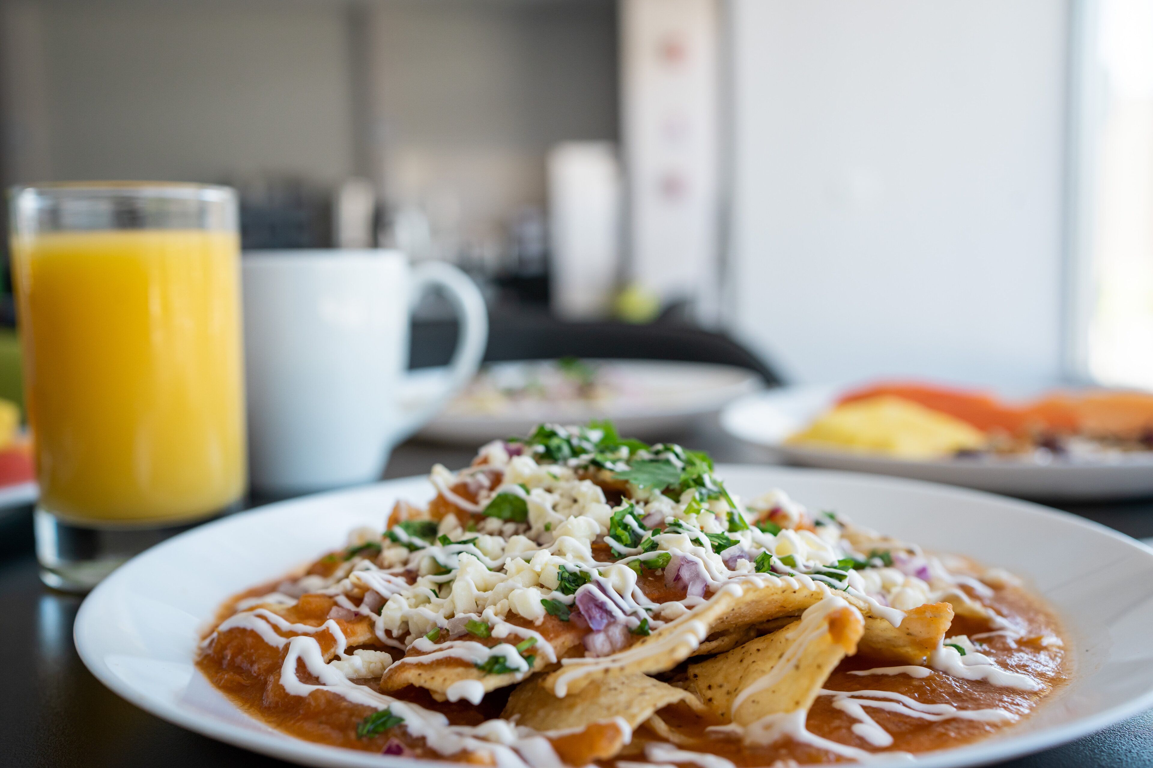 Un piatto di nachos con formaggio e un bicchiere di succo d'arancia.