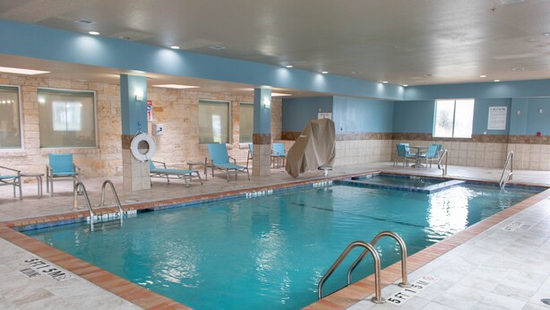 An indoor swimming pool with clear water, tiled walls, and blue chairs around the pool area. - Holiday Inn Express & Suites Temple - Medical Center Area by IHG (Temple)
