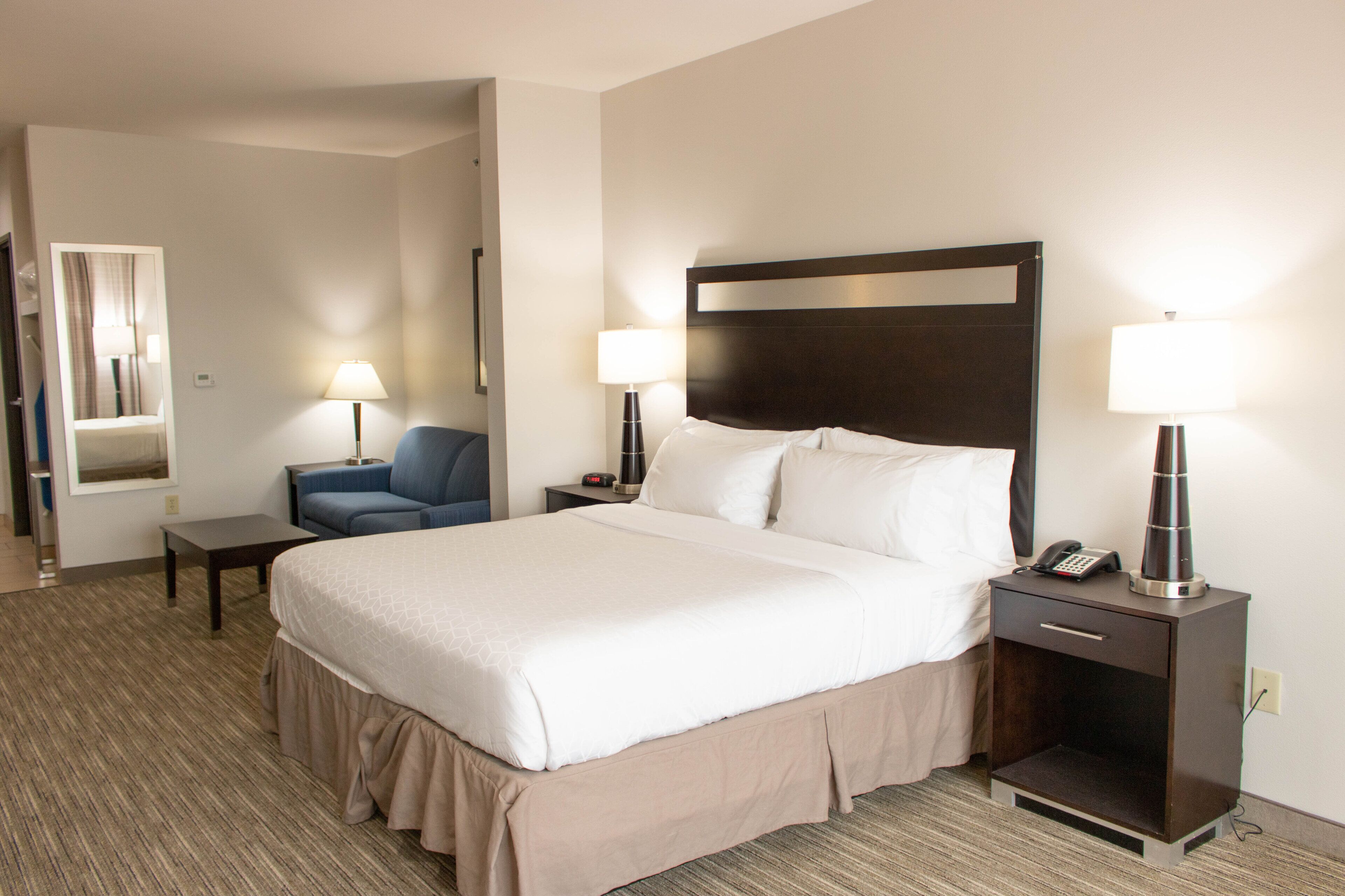 A hotel room with a large bed, two bedside tables with lamps, a chair, and a small table.