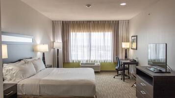 A hotel room with a bed, desk, chair, dresser, and a large window with curtains.