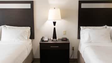 A hotel room with two beds, a nightstand with a lamp, a phone, and a digital clock.