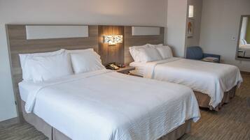 A hotel room with two beds, a nightstand, a chair, and a mirror.