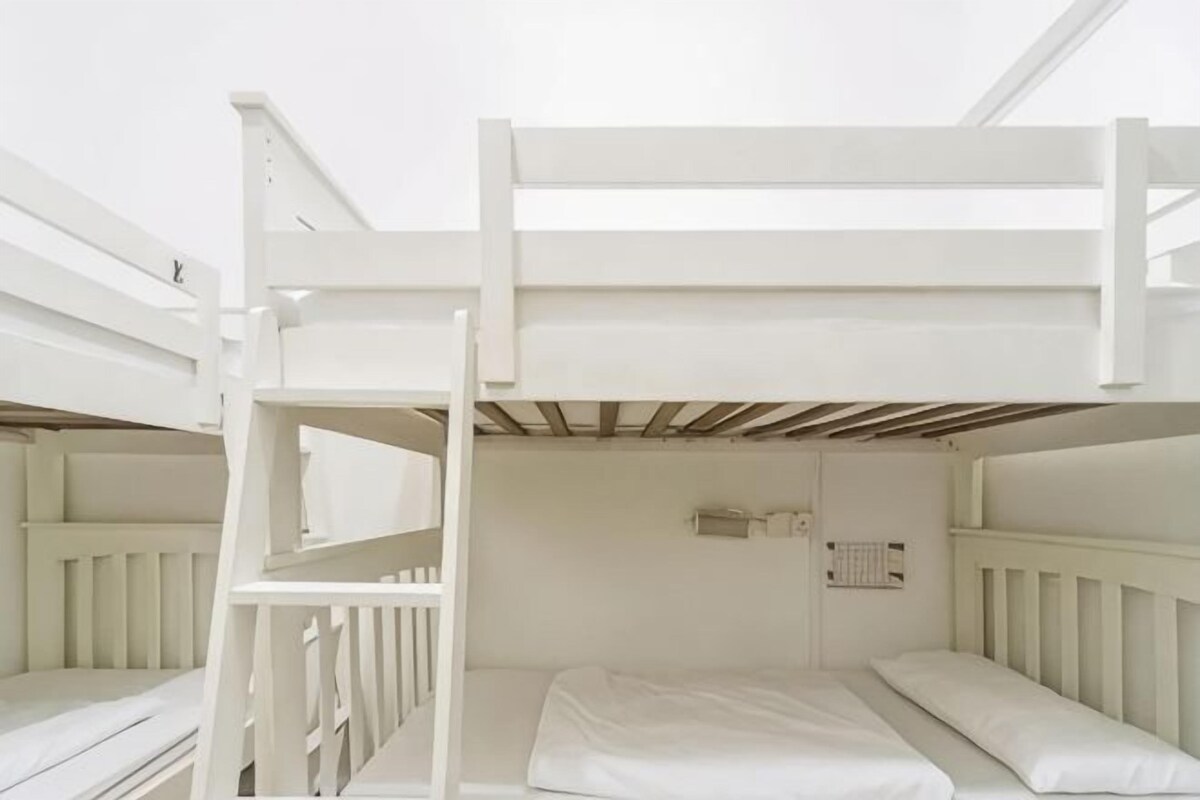 A bunk bed room with a ladder, a small window, and a radiator.