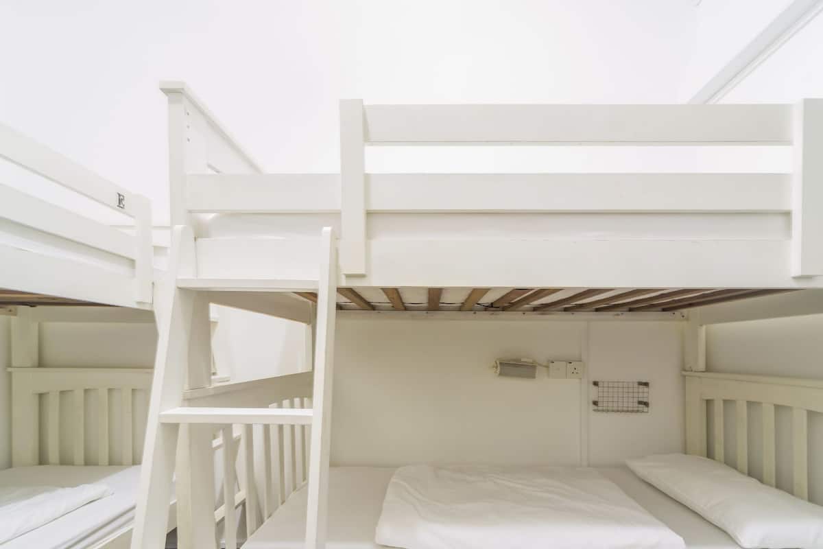 A bunk bed room with white railings and a wooden ceiling.