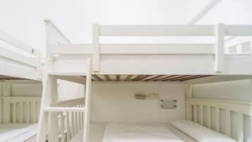 Une chambre avec un lit superposé, des barreaux blancs et un plafond en bois.