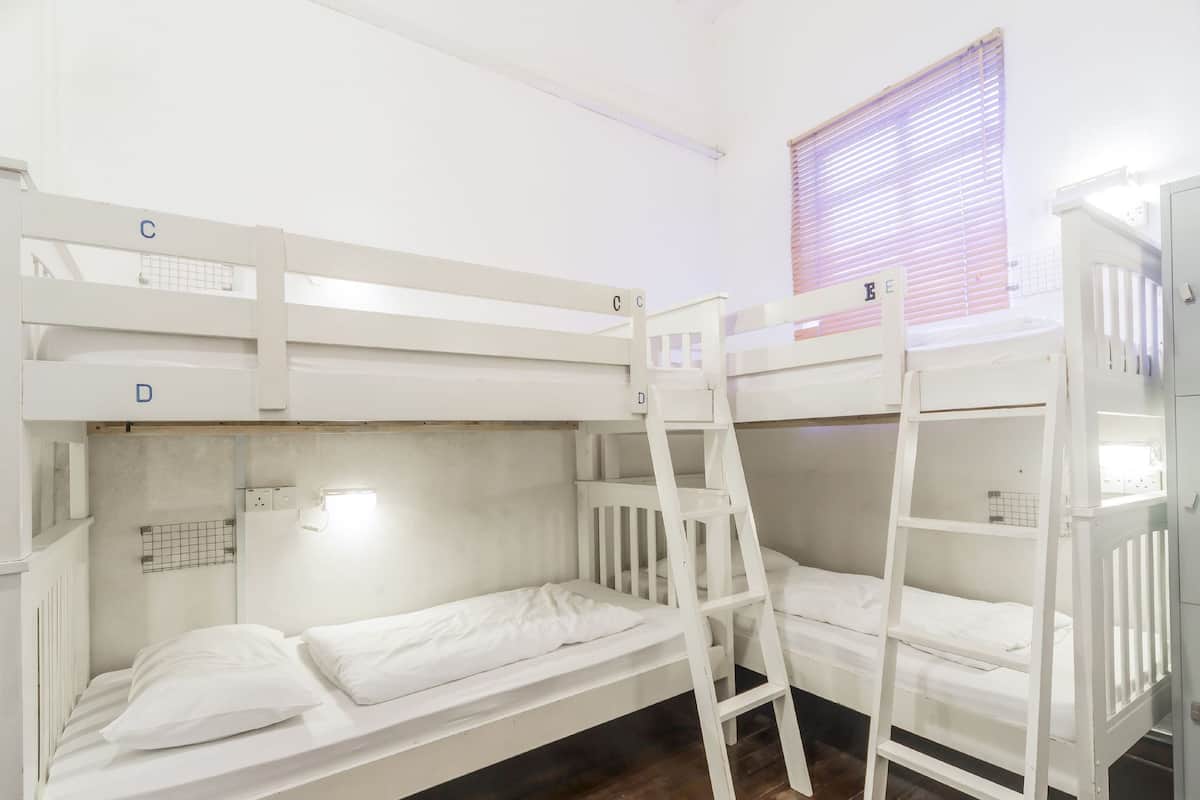 A bunk bed room with white beds and a ladder.