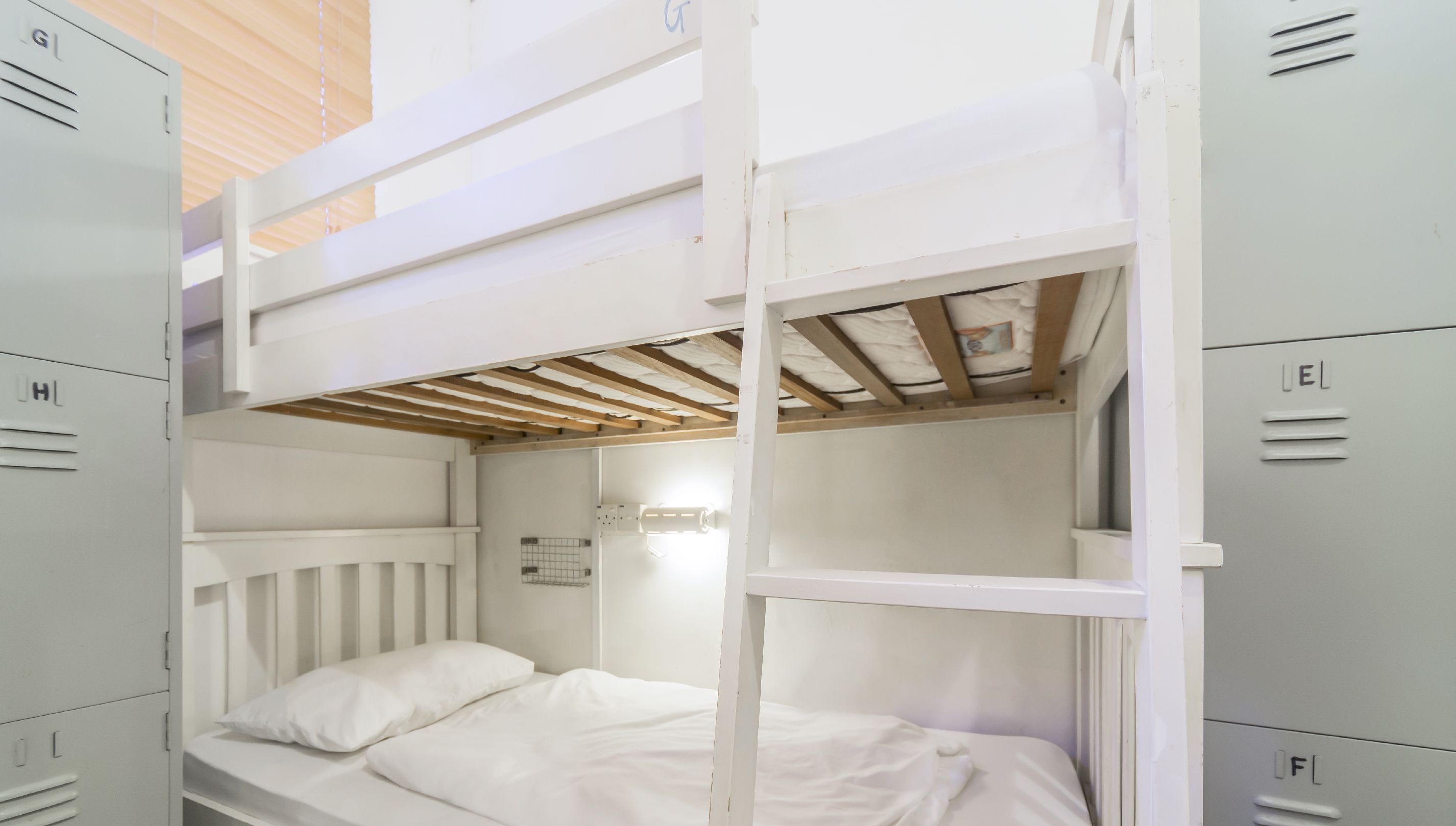 Une chambre avec des lits superposés, des casiers blancs de chaque côté et un plafond en bois.