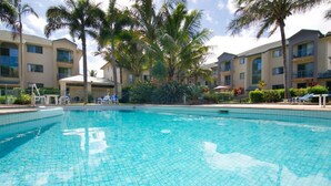 Una piscina rodeada de palmeras y un edificio con balcones.