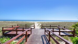 Una pasarela de madera que lleva a una playa con vista despejada al océano.