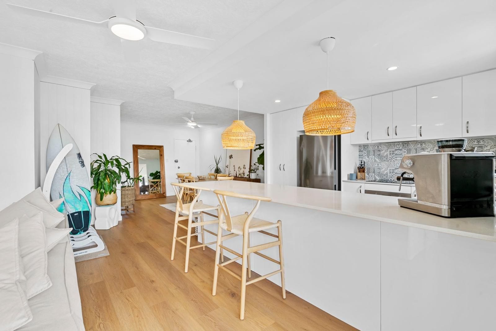 A modern kitchen with white cabinets, a central island, and a large island lamp.