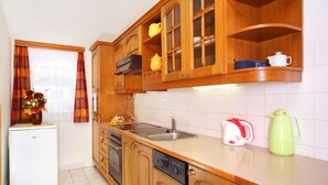 A kitchen with wooden cabinets, a built-in dishwasher, a sink, and a refrigerator. - Pension Villa Stella (Spindleruv Mlyn)