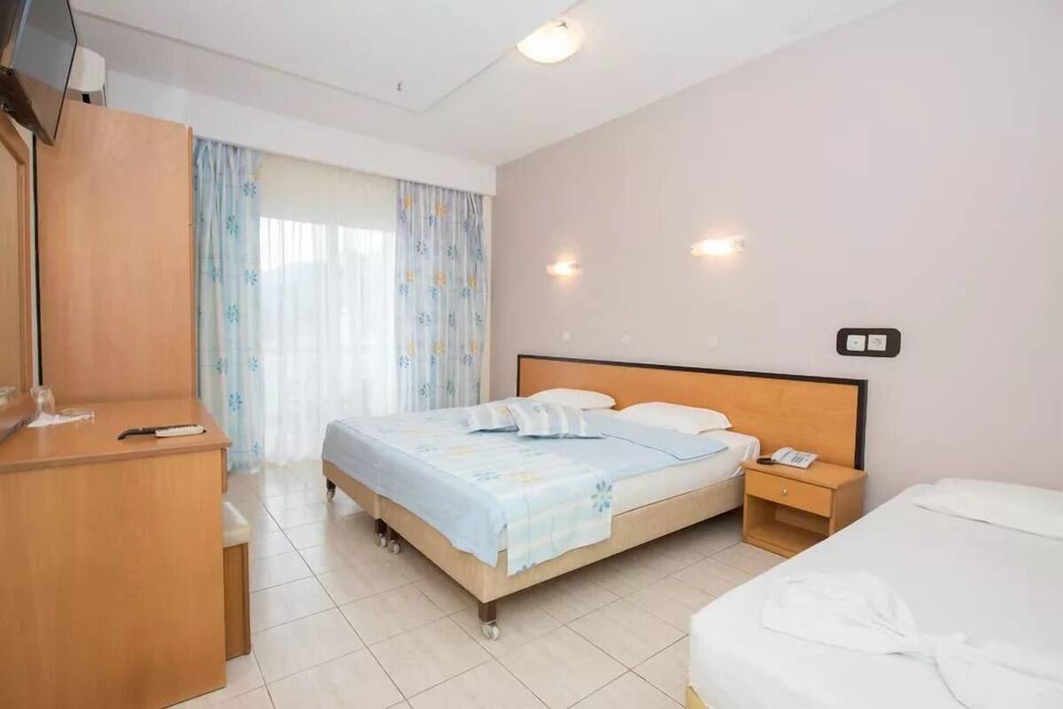 A hotel room with a bed, bedside table, and a wardrobe.
