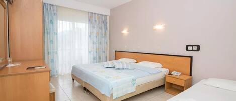 A hotel room with a bed, bedside table, and a wardrobe.