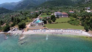 An aerial view of a coastal resort with a swimming pool, beach umbrellas, and a mountainous backdrop. - Maranton Beach Hotel (Thasos)