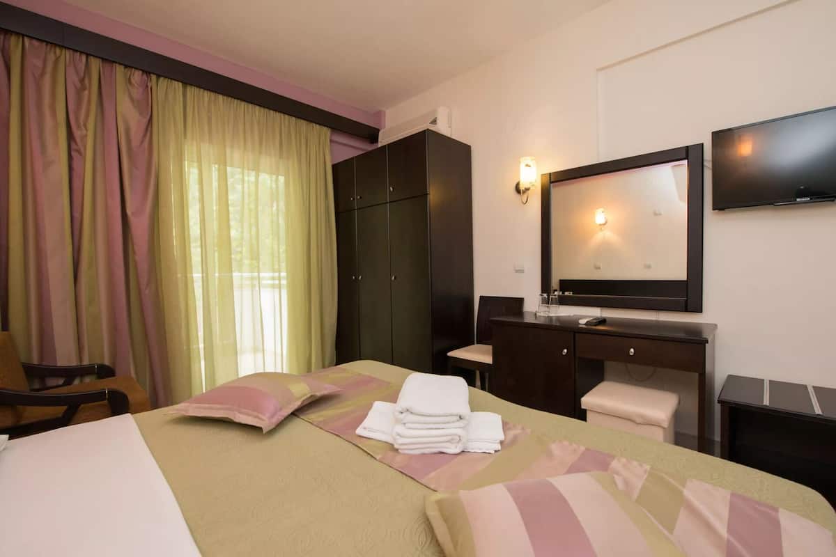 A hotel room with a bed, a desk, a chair, a wardrobe, and a TV.