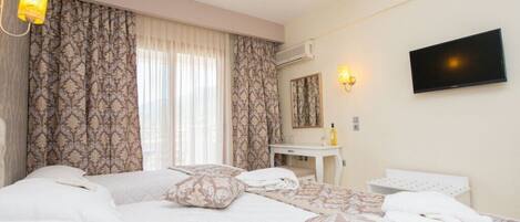 A hotel room with a large bed, a bedside table, a TV, and a window with curtains.