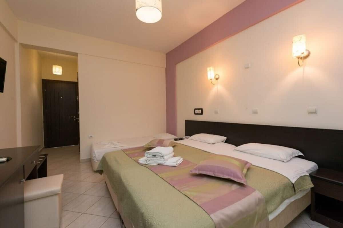 A hotel room with two beds, a desk, and a chair.