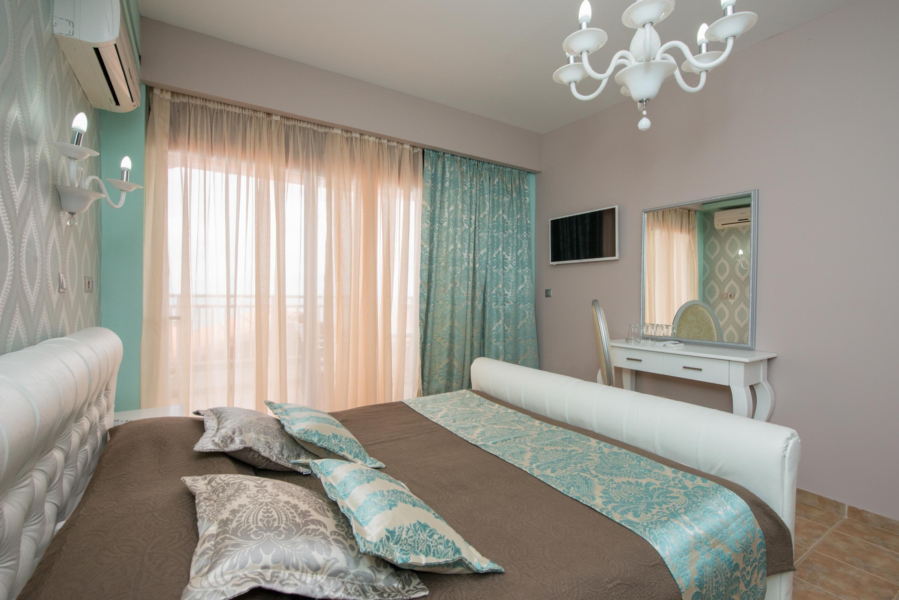 Une chambre d’hôtel avec un lit, une coiffeuse avec un miroir et un téléviseur fixé au mur.
