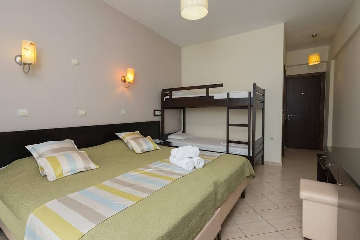 A hotel room with a bunk bed, a single bed, and a desk.