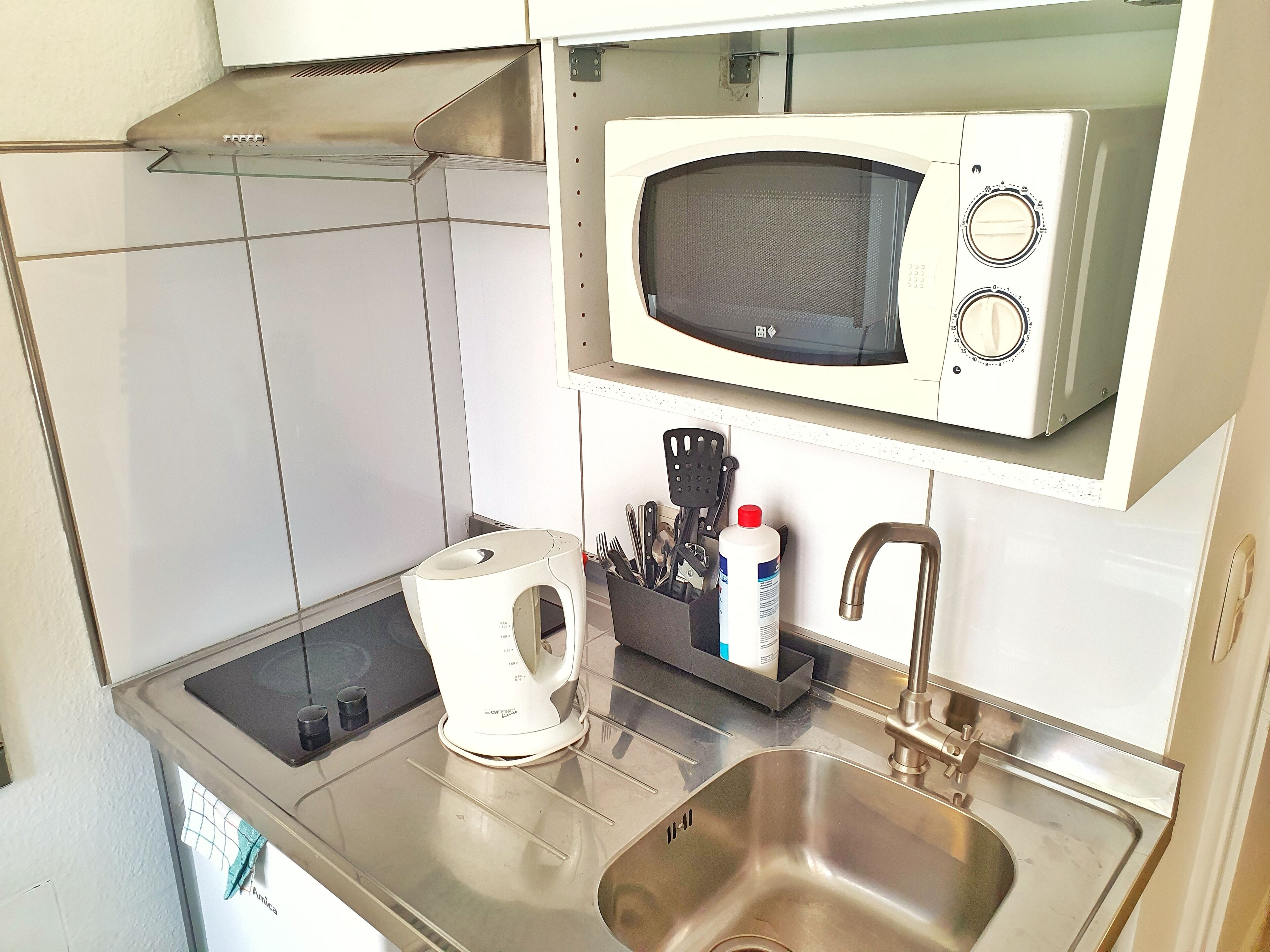 Eine moderne Küche mit Spüle aus Edelstahl, einer Mikrowelle und einem Wasserkocher.