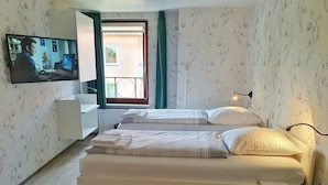 Un dormitorio con cama, mesita de noche y televisor montado en la pared.