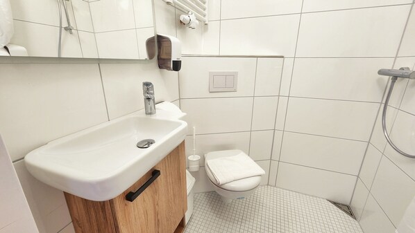 A bathroom with a white sink, toilet, and shower.