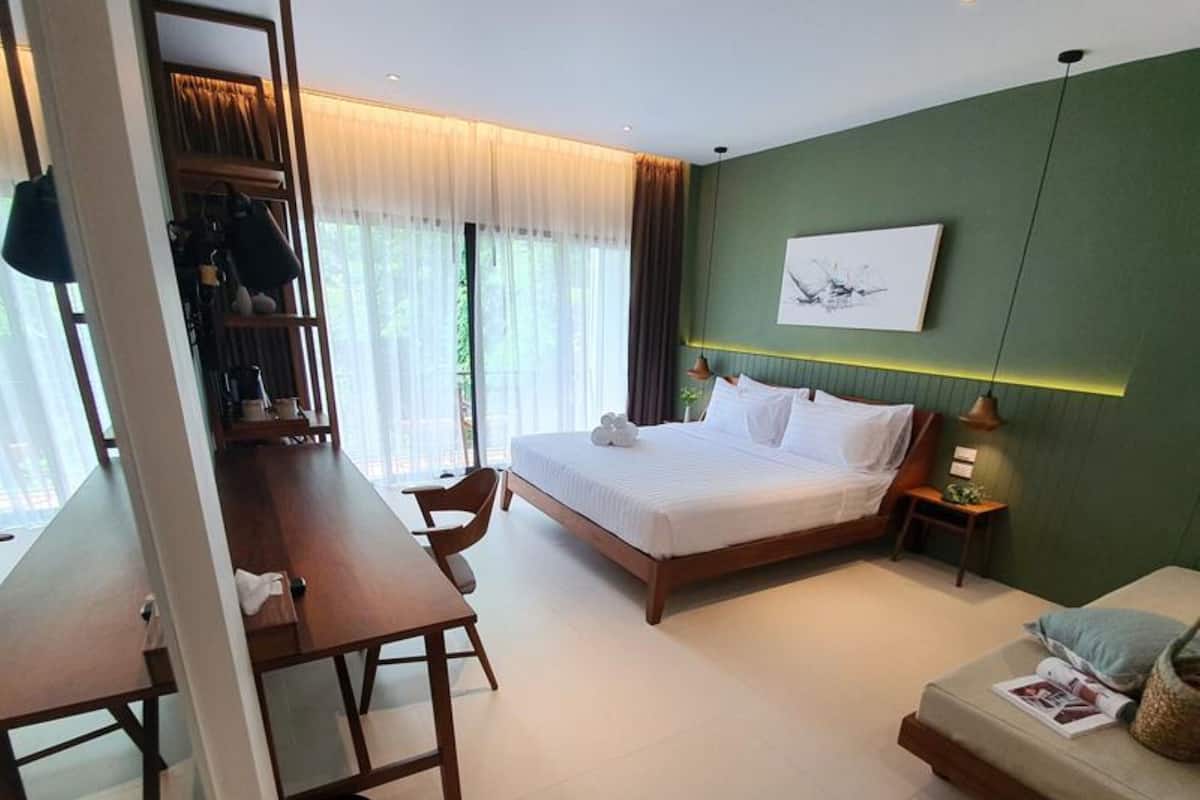 A modern hotel room with a large bed, a desk, and a seating area.
