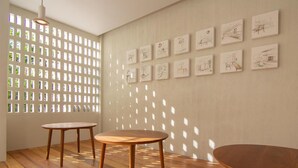 Une pièce dotée d’un plancher en bois, de deux tables rondes et d’un mur orné de dessins encadrés.