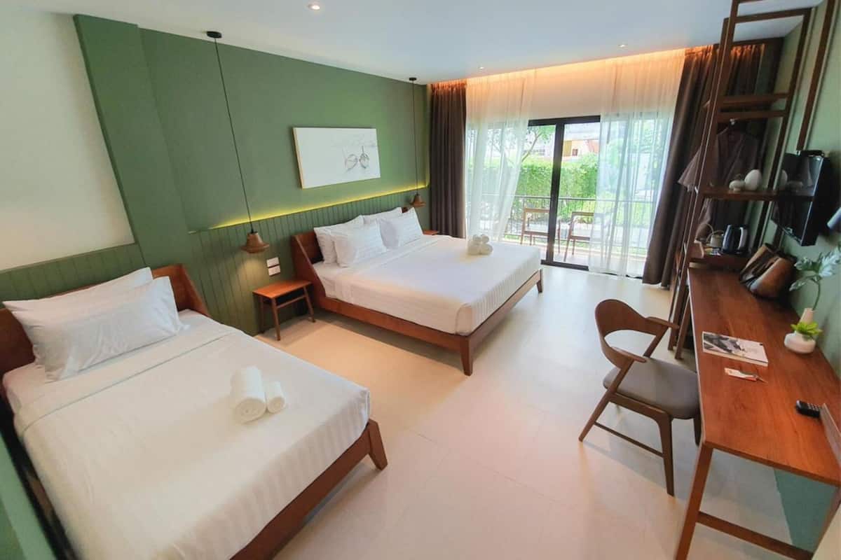 A hotel room with two beds, a desk, and a balcony with a view.