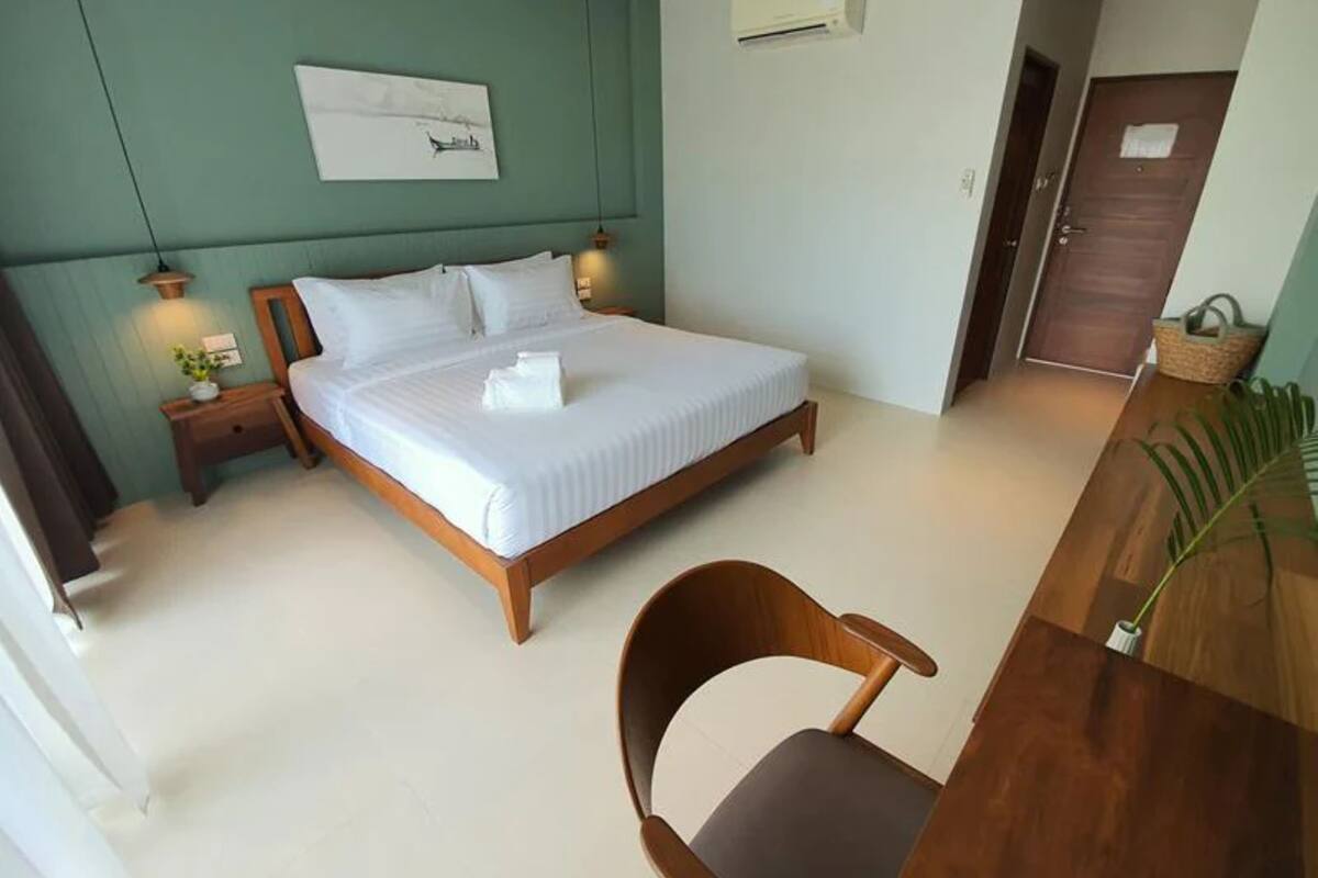 A neatly arranged bedroom with a bed, bedside tables, a chair, and a wall-mounted air conditioner.