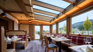 A restaurant with wooden furniture, large windows, and a view of the countryside. - Hotel Nesselwanger Hof (Nesselwang)