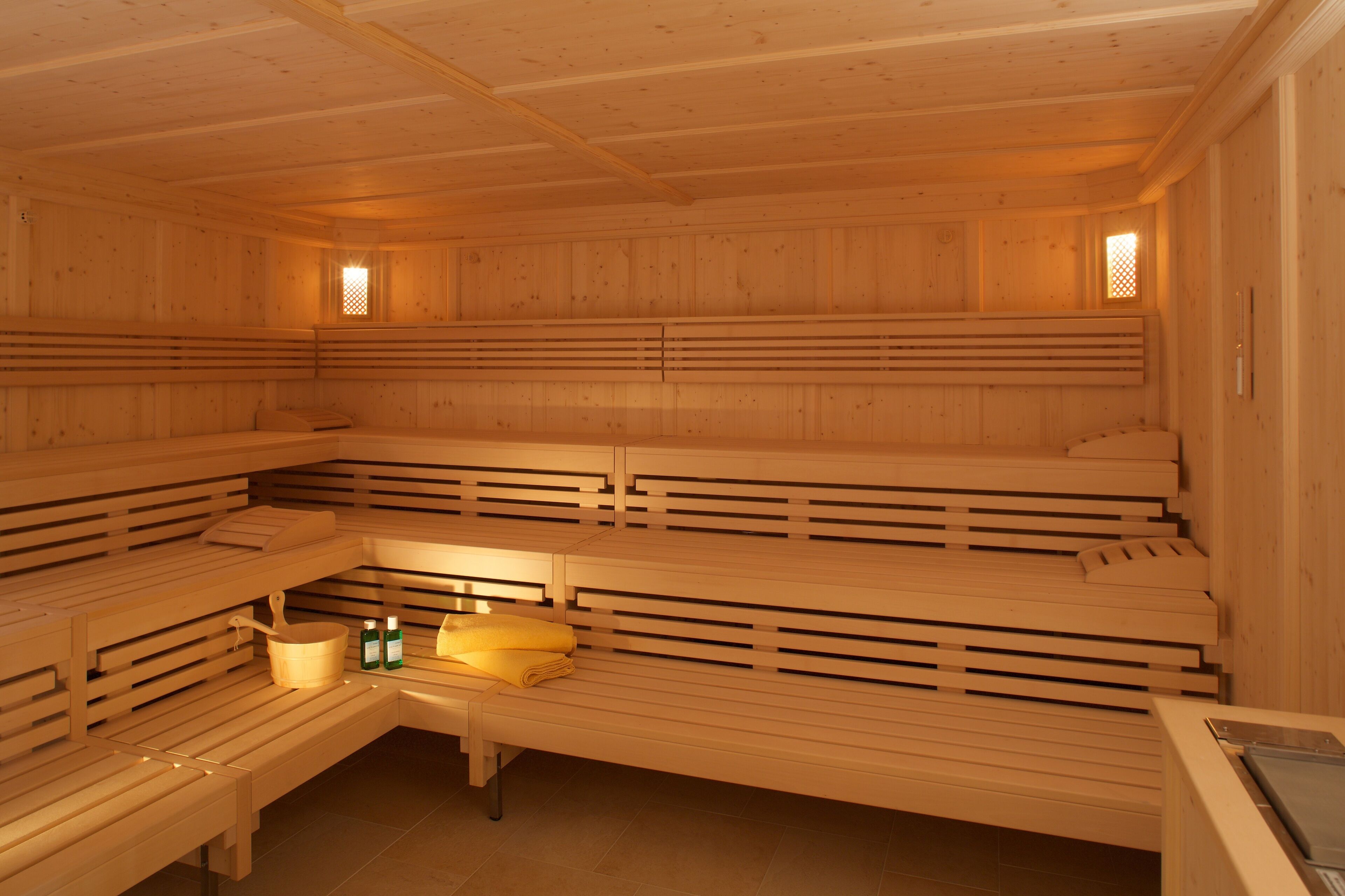 Una sauna con varios bancos y uno con toallas y botellas.